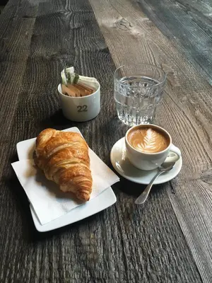 a table with a croissant and a cup of coffee at Rome Inn Vatican View Rooms in Rome