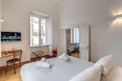 a bedroom with a large white bed and a desk at Corso charming suite in Rome
