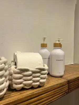 three bottles of soap and towels on a wooden shelf at Saint John House in Rome