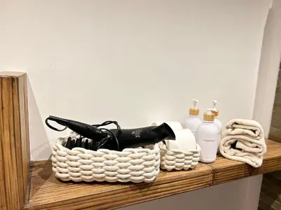 a basket of bathroom items on a wooden shelf at Saint John House in Rome