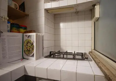 a white tiled kitchen with a stove and refrigerator at Delizioso loft vicino Piazza del Popolo in Rome