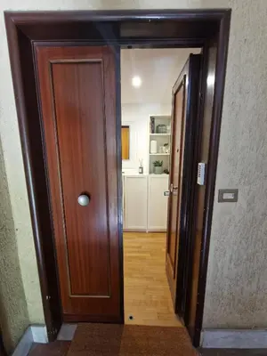 a wooden door leading to a hallway with a kitchen at Casa Claudia in Rome