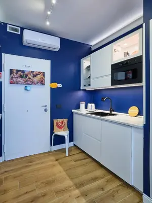 a kitchen with blue walls and a sink and a door at Merulanasuite Saint John in Rome