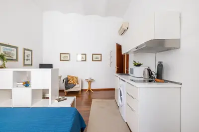 a kitchen with white cabinets and a blue bed in a room at Monti apartment in Rome
