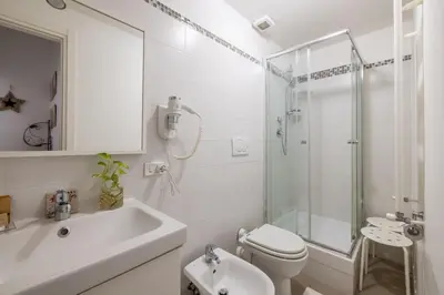 a white bathroom with a shower and a toilet and a sink at Monti apartment in Rome