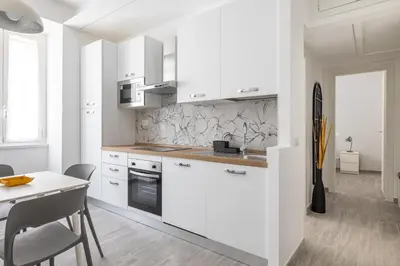 a kitchen with white cabinets and a table with chairs at Domus Ponte Lungo in Rome