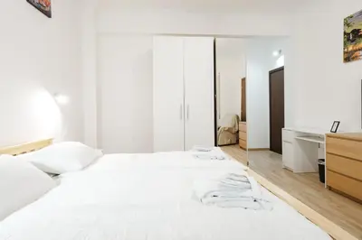 a white bedroom with a large bed and a desk at Gioele's Apartment in Rome