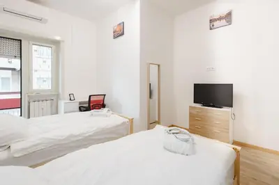 a bedroom with two beds and a flat screen tv at Gioele's Apartment in Rome