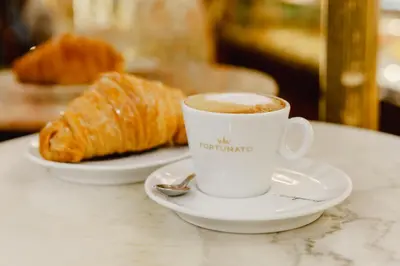 a cup of coffee and a croissant on a table at Gioele's Apartment in Rome