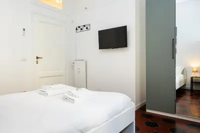 a white bedroom with a bed and a tv on a wall at Fernando’s Apartment in Rome