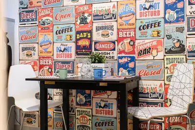 a table with two chairs in front of a wall covered in soda signs at Sanniti Luigi Cozy Home in Rome
