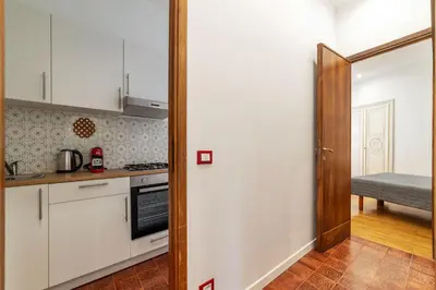 a kitchen with white cabinets and a door to a room at GuestHost - Bright Apartment X4 along the Tevere! in Rome