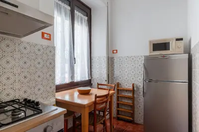a kitchen with a table and a refrigerator at GuestHost - Bright Apartment X4 along the Tevere! in Rome
