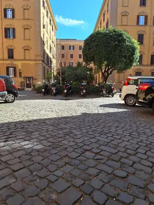 a cobblestone street with cars parked in front of buildings at Casa Sommeiller in Rome