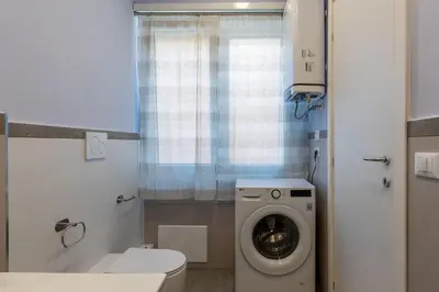a bathroom with a toilet and a washing machine at GuestHost - Studio Apartment MM Cipro Rome in Rome