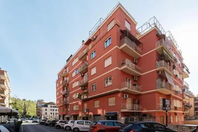 a red building with cars parked in front of it at GuestHost - Studio Apartment MM Cipro Rome in Rome