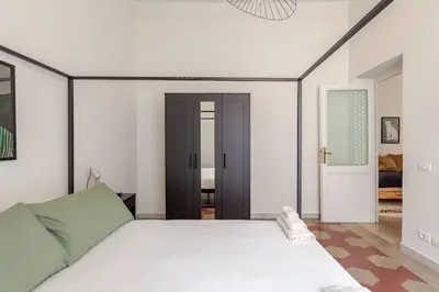 a bedroom with a white bed with a black headboard at RL Apartment in Rome