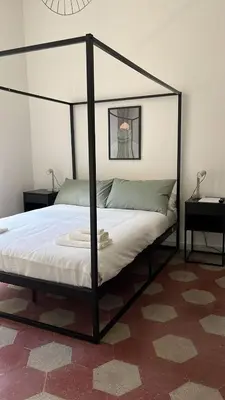 a black canopy bed in a room with two tables at RL Apartment in Rome