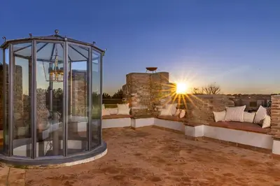 a glass gazebo on a patio with the sunset at Torre della Luna Roma Lusso, Privacy e Piscina con Vista su San Pietro in Rome