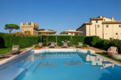a pool with chairs and umbrellas next to a building at Torre della Luna Roma Lusso, Privacy e Piscina con Vista su San Pietro in Rome