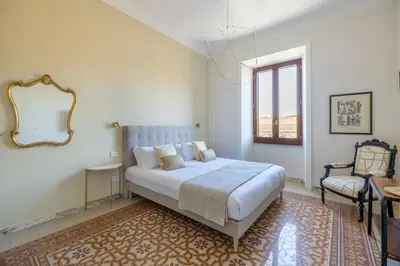 a bedroom with a bed and a mirror and a chair at Stylish 3BR between Vatican & City Center in Rome