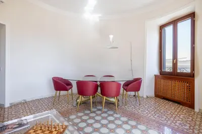 a dining room with a table and red chairs at Stylish 3BR between Vatican & City Center in Rome