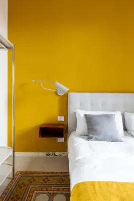 a bedroom with a yellow wall and a bed at Stylish 3BR between Vatican & City Center in Rome