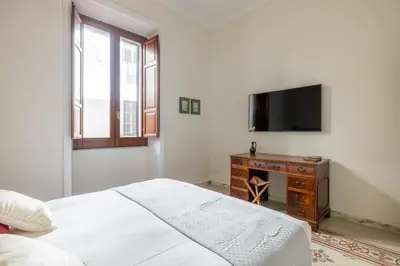 a white bedroom with a bed and a television at Stylish 3BR between Vatican & City Center in Rome