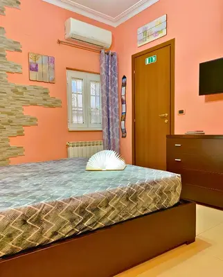 a bedroom with orange walls and a bed and a television at The Best Nest in Rome