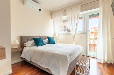 a white bedroom with a bed with blue pillows at L'Attico di Katia in Rome