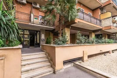a building with stairs and palm trees in front of it at St Peter Vatican Lovely Apartment & Patio, Rome in Rome