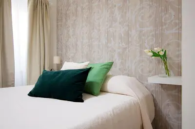a bed with green pillows and a vase with flowers on it at St Peter Vatican Lovely Apartment & Patio, Rome in Rome