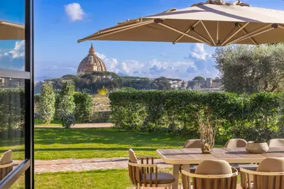 a patio with an umbrella and a table and chairs at Exclusive Home with pool and iconic View on Saint Peter in Rome
