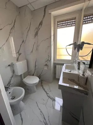 a white bathroom with a toilet and a sink at Gladiatrice Suite in Rome