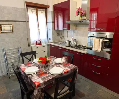 a kitchen with red cabinets and a table with chairs at Mancinelli Rome Apartment in Rome