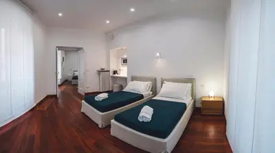 two beds in a room with wooden floors at Habitat 42 Roman Stay in Rome