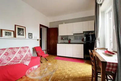 a living room with a red couch and a kitchen at Le Note Di Angela in Rome