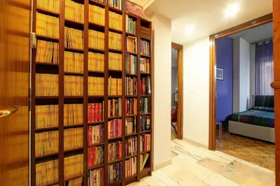 a room with a wall of book shelves filled with books at Le Note Di Angela in Rome