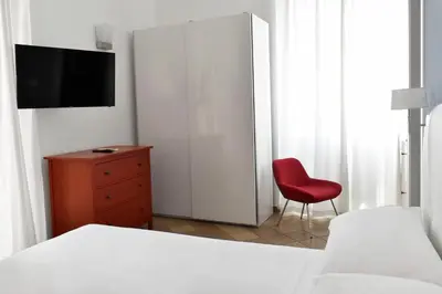 a bedroom with a bed and a red chair at Roma Resort Colosseum in Rome