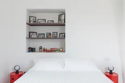 a bedroom with a white bed and shelves at HospitalityRome Vittorio Emanuele in Rome