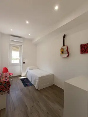 a white bedroom with a bed and a guitar on the wall at Casa Vacanze LaMatta Music House in Rome