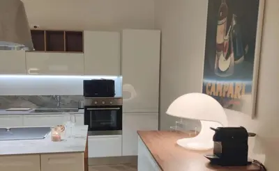 a kitchen with white cabinets and a table with a lamp at Casa Beatrice, Trastevere in Rome