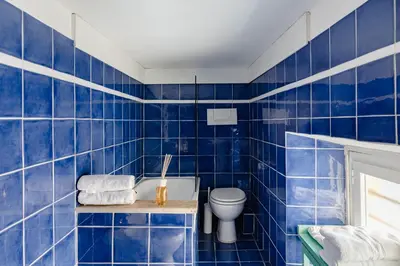 a blue tiled bathroom with a toilet and a sink at Trevi Fountain - Modern Suite in 17th-century Palazzo in Rome