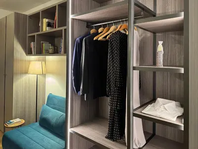 a walk in closet with a blue chair and clothes at Labicum XXII - Modern Luxury Studio near the Colosseum in Rome