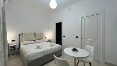a white bedroom with a bed and a table and chairs at Antony house in Rome