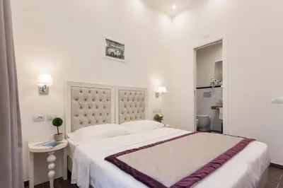 a white bedroom with a large bed and a table at Relais Monti in Rome