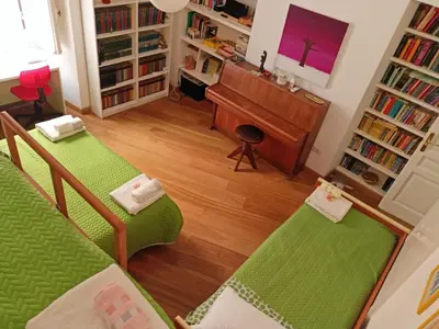 a living room with two green beds and a piano at Private room by an Italian family - A unique experience close to Colosseum, the Roman Forum and Basilica Saint Mary Major in Rome