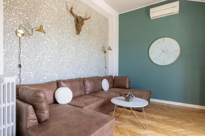 a living room with a brown couch and a clock on the wall at Dolce Vita Penthouse in Rome