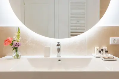 a bathroom sink with a vase of flowers and a mirror at Amazing Via del Corso 277 Suites in Rome