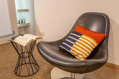 a black chair with a pillow and a book at Glam Nest & Garden Colosseum in Rome